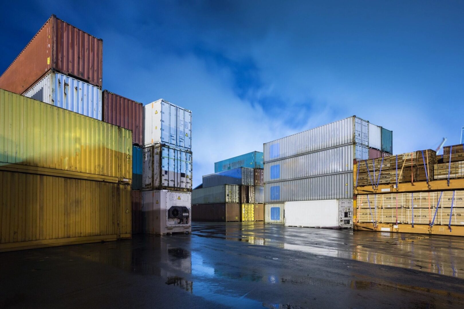 A bunch of containers are stacked up in the rain.