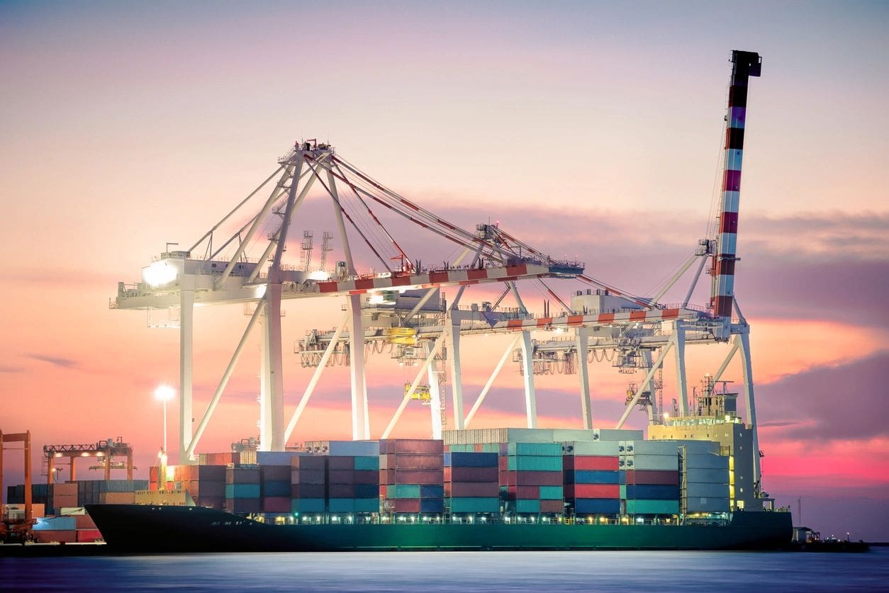 A large cargo ship in the ocean at dusk.