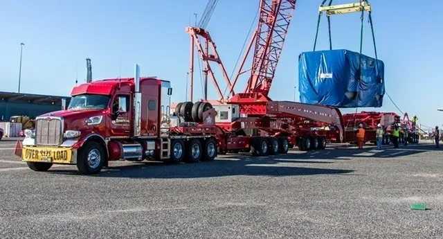 A red truck is parked next to a crane.