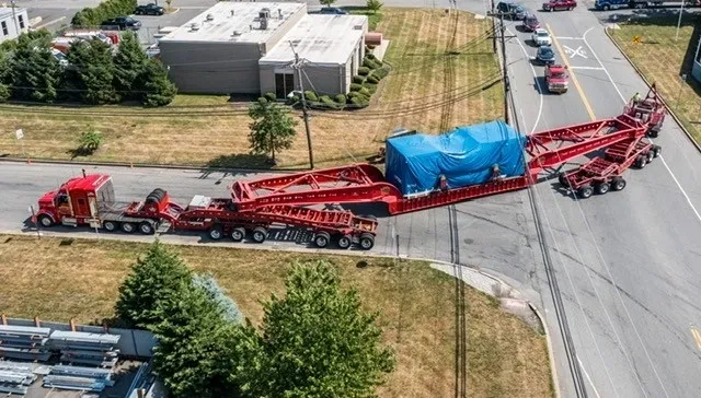 A large red truck is pulling a blue trailer.